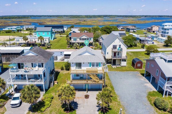 A coastal residential area with multiple two-story houses, a visible garage, and a clear view of the ocean.
