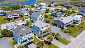 An aerial view of a coastal residential area with houses, a marina, and a large body of water in the background.