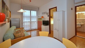 A compact living space with a dining area, kitchenette, and a television.
