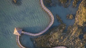 An aerial view of a winding wooden bridge connecting a small island to a larger landmass, surrounded by water and vegetation. - Spacious apartment with terrace in Rosolina Mare (Rosolina Mare)
