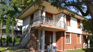 Un bâtiment à deux étages doté d’un balcon, d’un escalier et d’un espace extérieur aménagé pour s’asseoir.