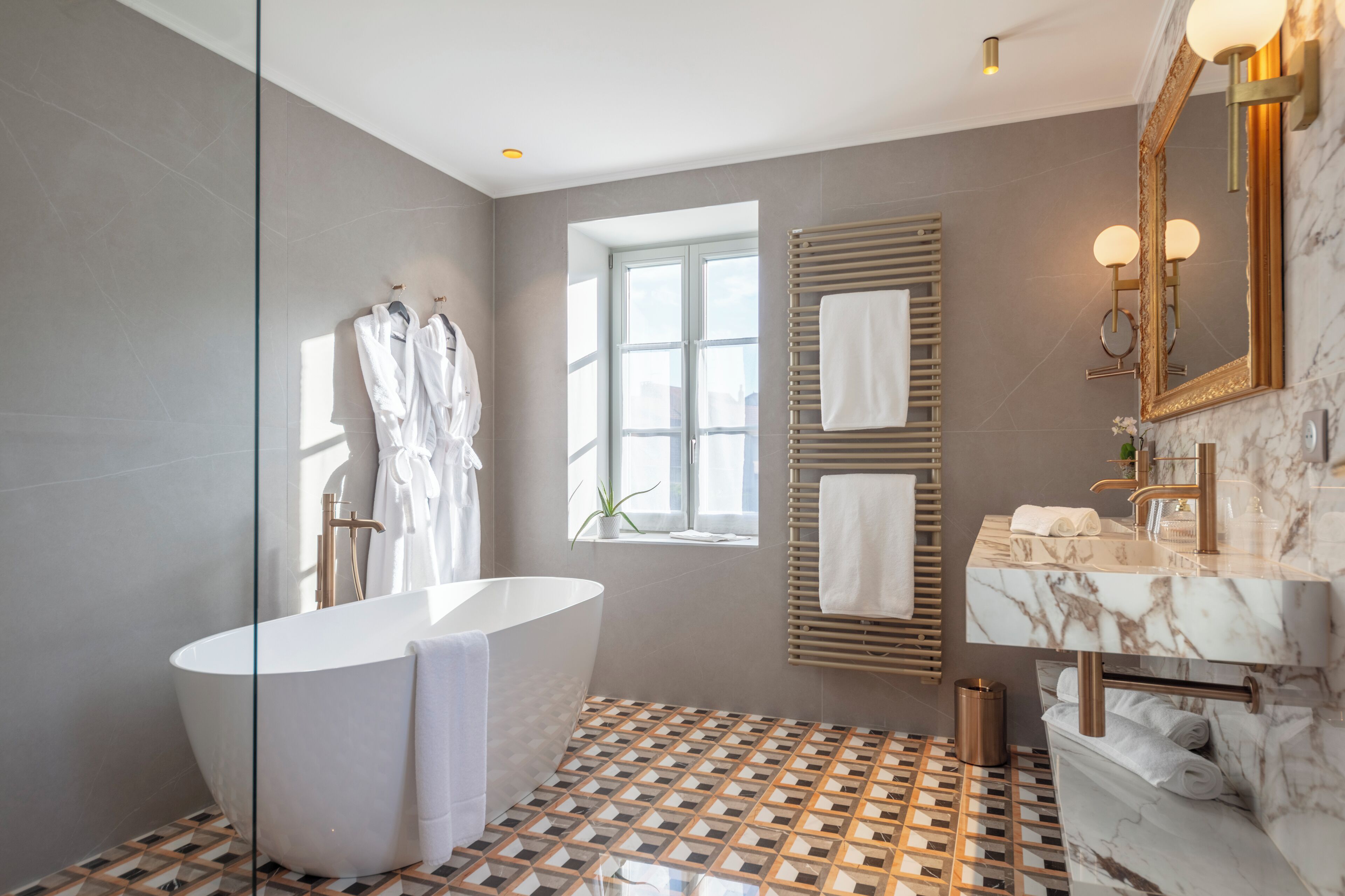 A modern bathroom with a freestanding bathtub, a large mirror, and a marble vanity.