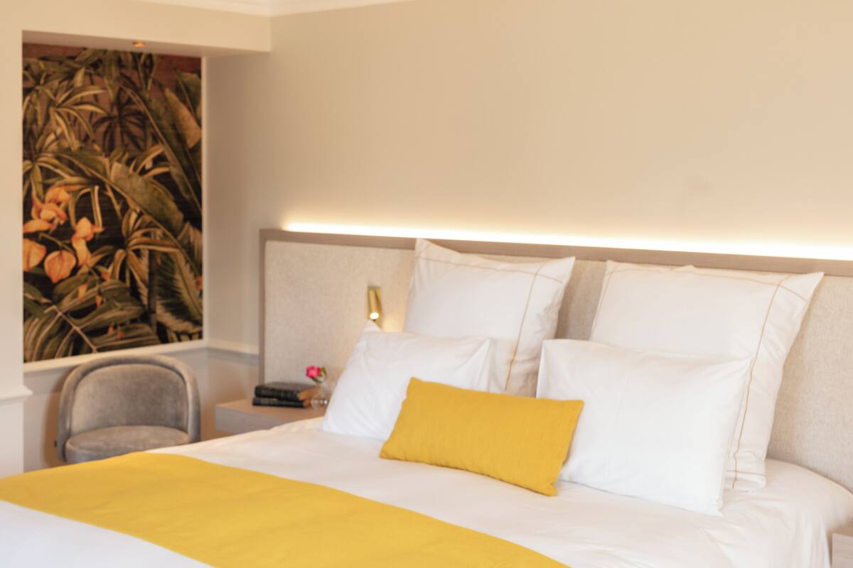 A hotel room with a bed, a nightstand, a chair, and a painting on the wall.