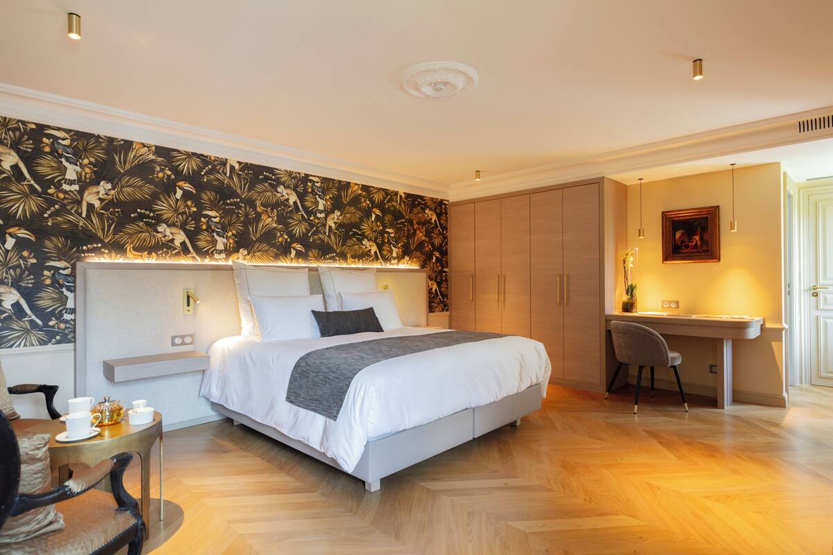 A modern bedroom with a large bed, a desk, and a chair.
