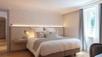 Ein modernes Schlafzimmer mit einem großen Bett, Nachttischen und Blick ins Freie durch ein Fenster.