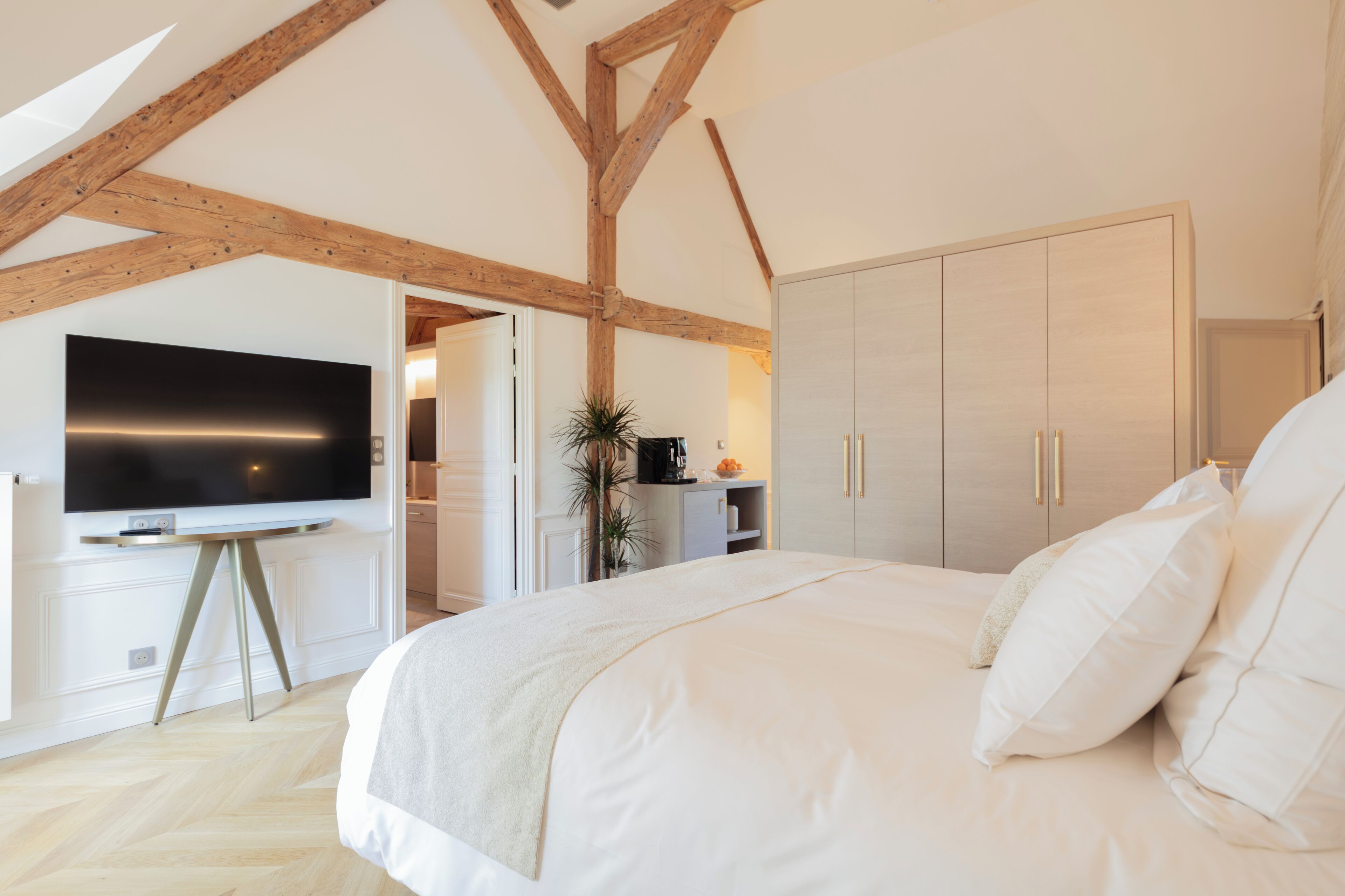 A bedroom with a large bed, a TV, and a wardrobe.