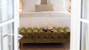 A bedroom with a bed, white pillows, a green upholstered headboard, and a wall mural of mountains and palm trees. - Le Clos Alice (Arbois)