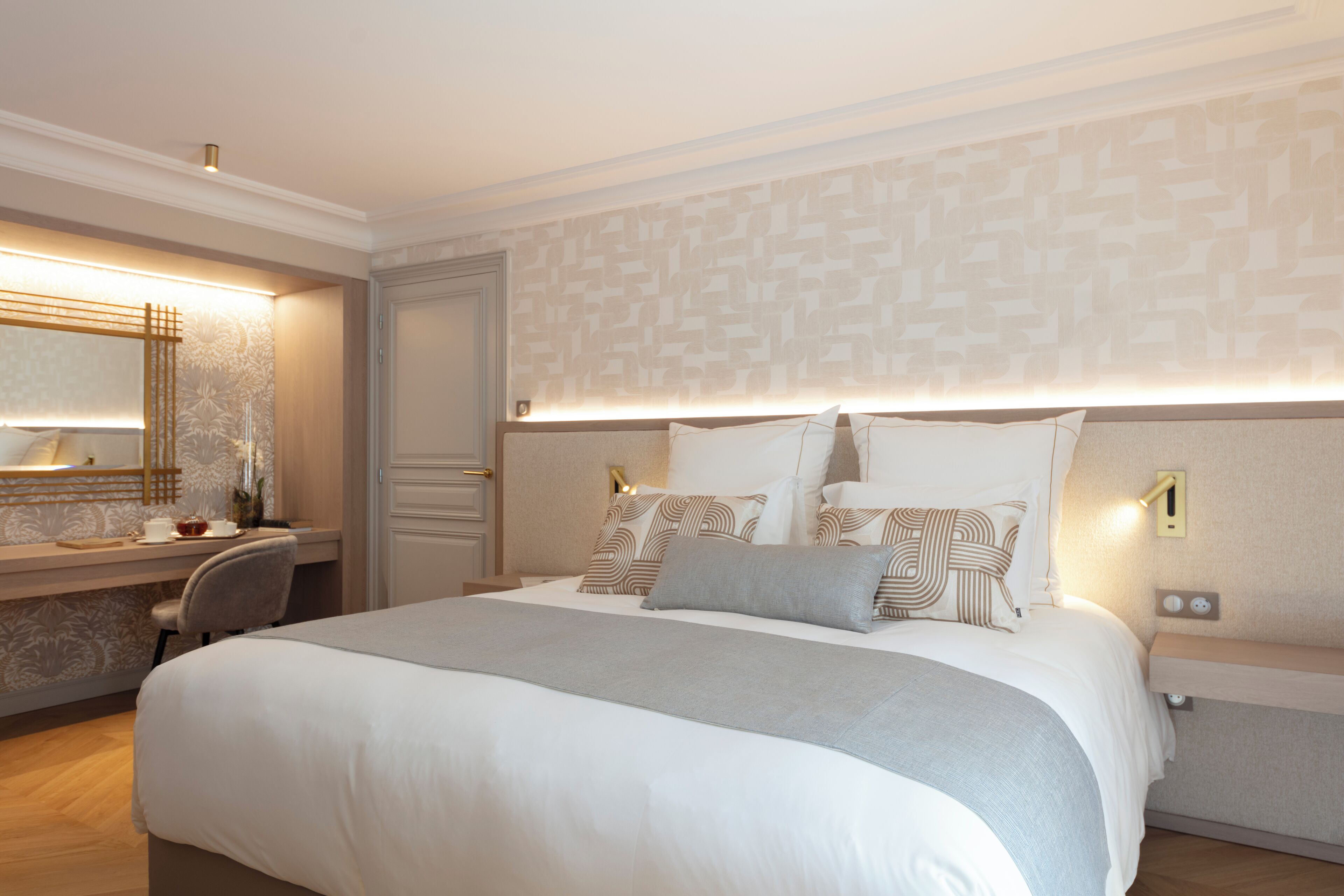 A hotel room with a large bed, bedside tables, a desk, and a mirror.