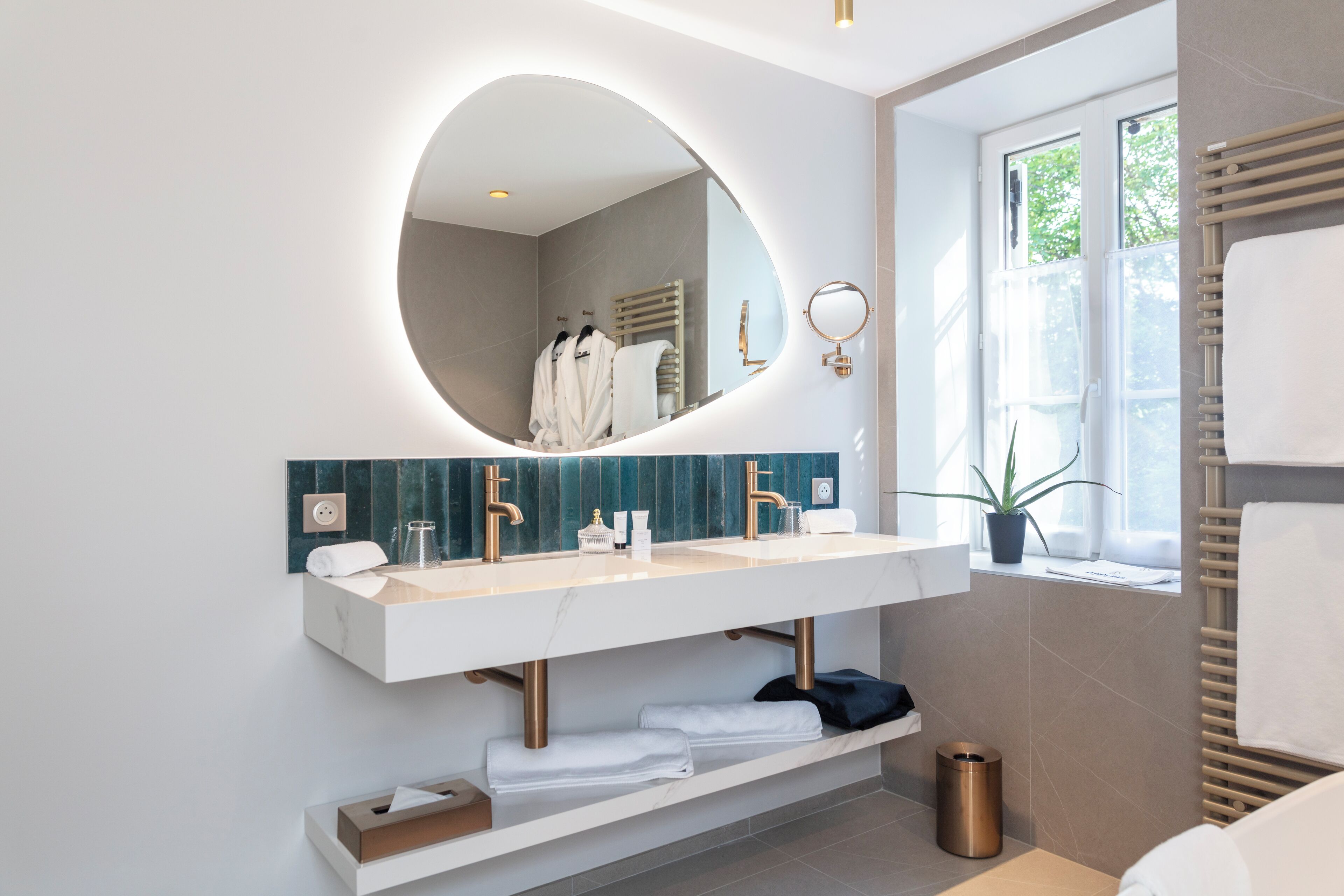 Ein modernes Badezimmer mit großem Spiegel, zwei Waschbecken und einem Handtuchhalter neben dem Fenster.