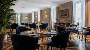 A spacious dining area with high ceilings, elegant chandeliers, and large windows allowing natural light. - Le Clos Alice (Arbois)