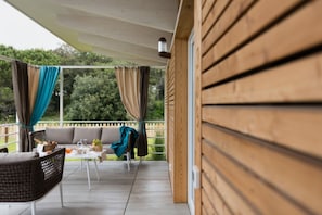 A covered outdoor seating area with a sofa, chairs, and a table.