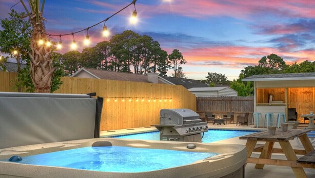 Un patio trasero con un jacuzzi, una parrilla de barbacoa y una terraza de madera.