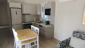 Una cocina compacta con armarios blancos, una mesa de comedor de madera y un sofá con cojines estampados.