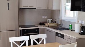 Una cocina moderna con armarios blancos, una mesa de comedor de madera y un microondas negro.