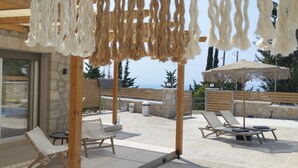 Un espacio al aire libre techado con sillones de descanso y una piscina.