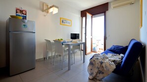 A compact room with a kitchenette, a dining area, and a bed. - Enjoyable house that overlooks the sea (Bibione)