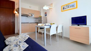 A compact living space with a kitchenette, a dining area, and a television. - Enjoyable house that overlooks the sea (Bibione)