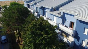Une rangée de bâtiments modernes de couleur bleu clair, dotés de toits plats, qui font probablement partie d’un hôtel ou d’un complexe touristique, et qui offrent une vue sur une plage et la mer.