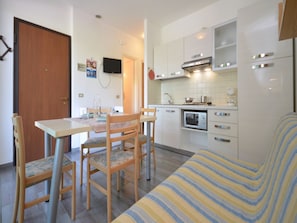 A compact kitchen with a dining area, a sofa, and a television. - Adorable modern holiday flat (Bibione)