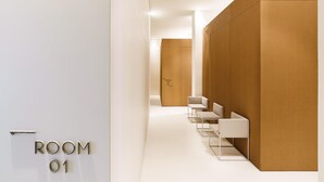 A modern hotel room with a wooden panel wall, a reception desk, and a seating area with chairs. - Meo Design Suite & Spa (Catania)
