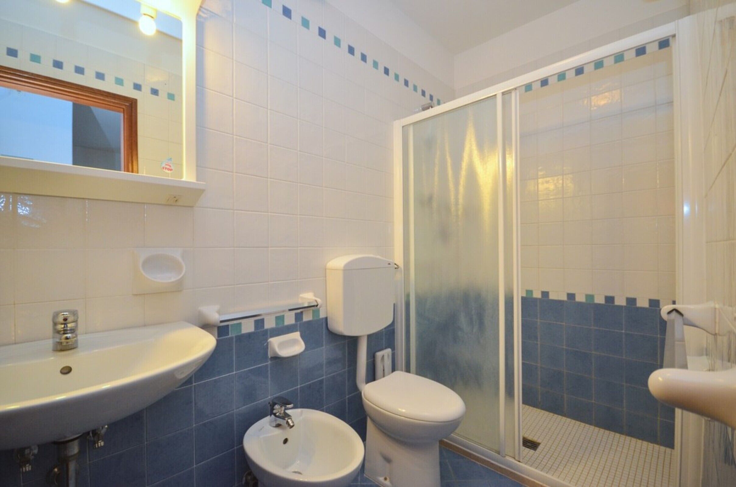 Une salle de bain équipée d’un lavabo, de toilettes et d’une douche à parois de verre.