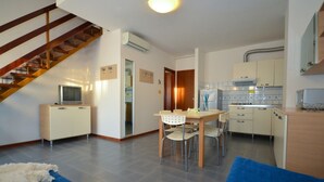 A compact living space with a dining area, kitchen, and a staircase. - Spacious seafront flat - Beahost (Bibione)