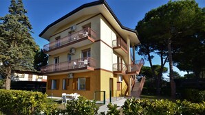 Un immeuble à plusieurs étages doté de balcons, de climatiseurs et d’un escalier menant à un niveau supérieur.