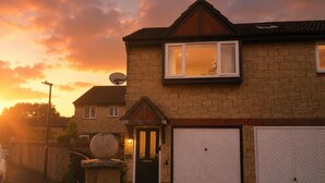 A two-story house with a garage, a satellite dish, and a well-maintained garden. - Family Friendly Coach House - Parking - Sleeps 4 (Weston-super-Mare)