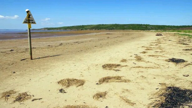 A beach with a warning sign, sandy terrain, and sparse vegetation. - Family Friendly Coach House - Parking - Sleeps 4 (Weston-super-Mare)