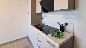 Una cocina moderna con extractor negro, un lavamanos y una encimera con una planta y utensilios.