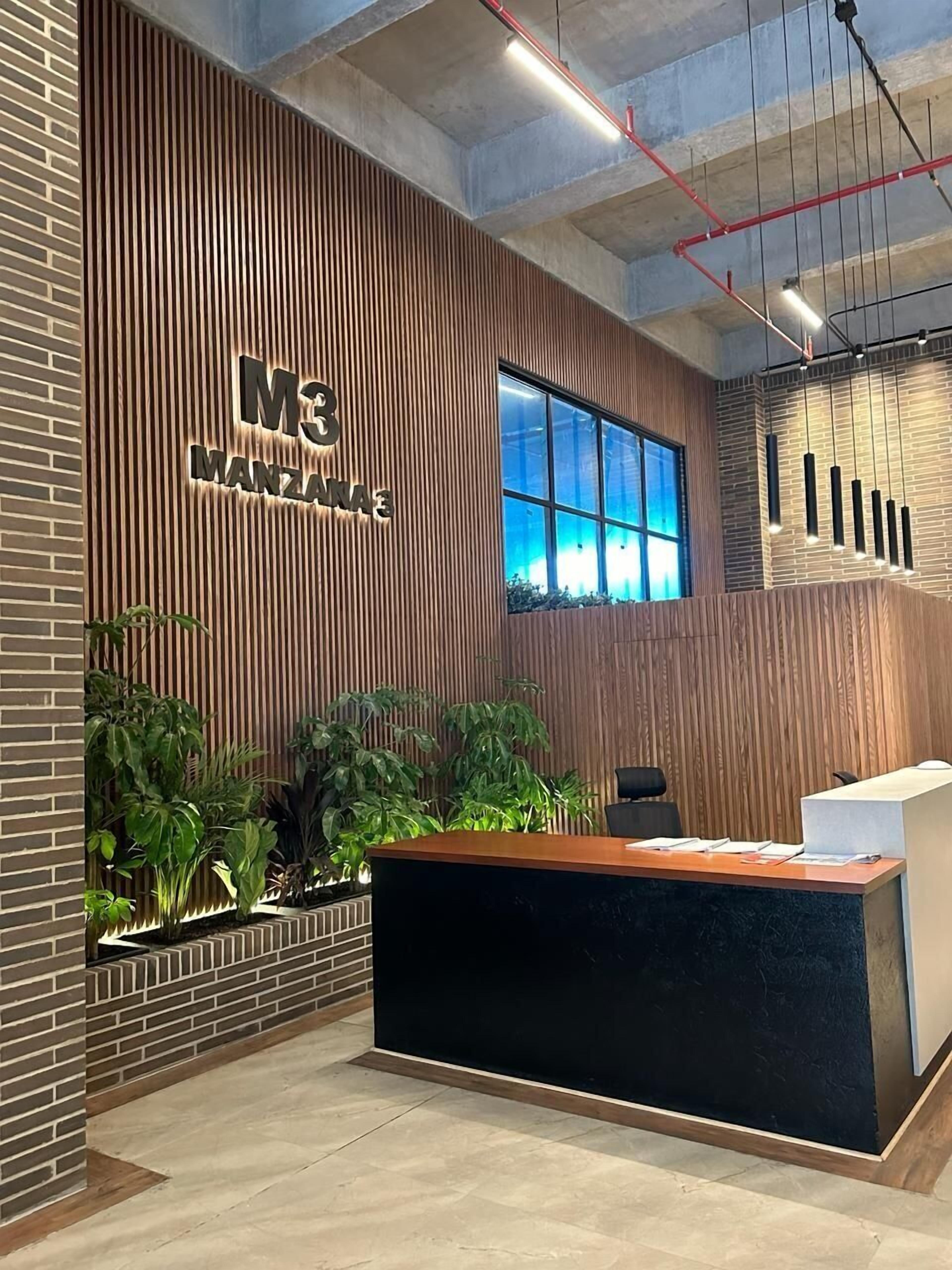 A reception desk with a wooden panel wall, a large window, and hanging pendant lights.