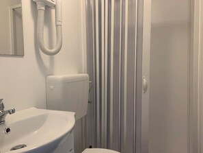 A bathroom with a white sink, toilet, and a shower curtain with vertical stripes. - ZEcamping 4 étoiles animé parc aquatique dog friendly mobil-home clim (Meta di Sorrento)