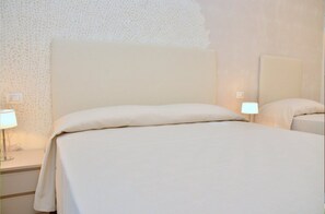 Une chambre d’hôtel avec un grand lit, une table de chevet avec une lampe et un miroir fixé au mur.