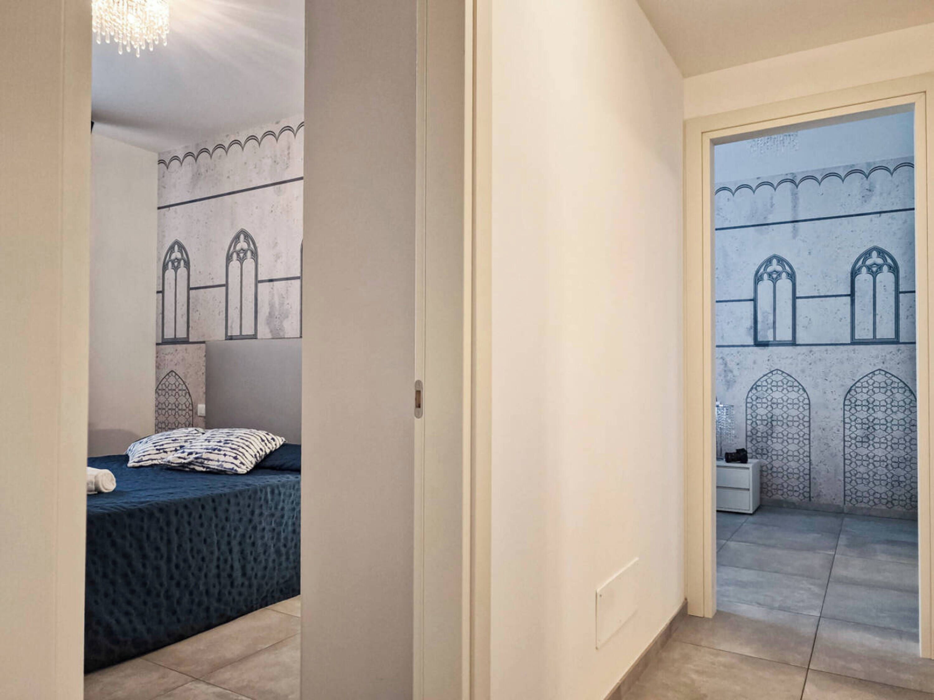 Un dormitorio con cama, mesita de noche y vista a un patio con arcos.