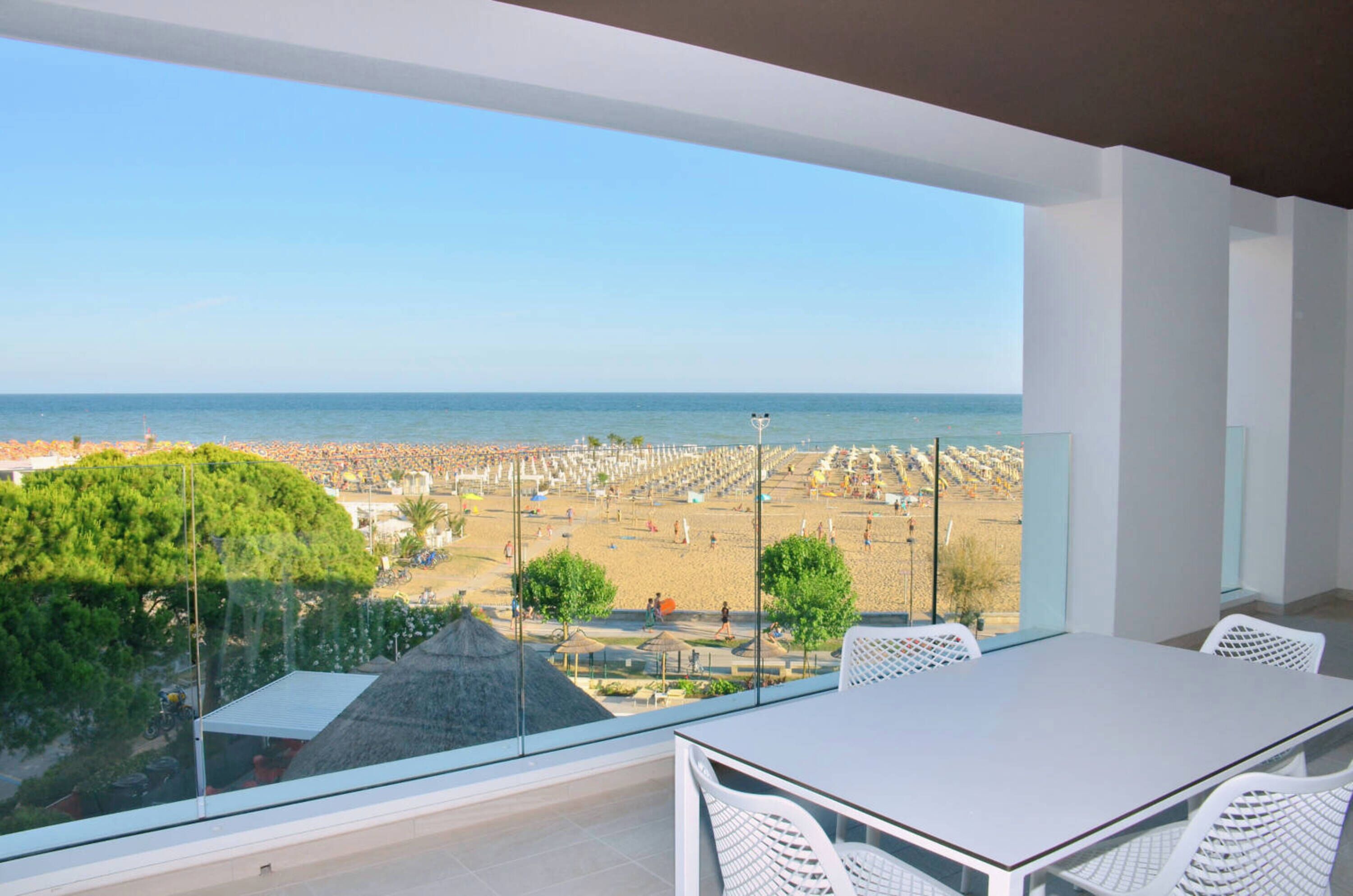 A balcony with a view of a beach and the sea.