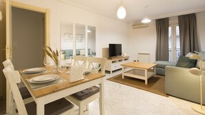 Un soggiorno moderno con zona pranzo, un divano, una TV e una lampada.