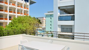A balcony with a table and chairs, overlooking a pool and adjacent buildings. - Beautiful apartment lighted by the sun in Bibione (Bibione)