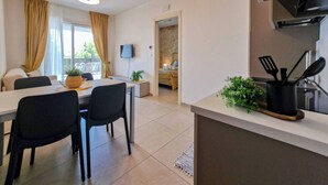 A modern apartment with a dining area, a kitchen, and a living room. - Azure serenity modern sea view flat with pool (Bibione)