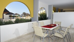 A dining area with a table and chairs, a red tablecloth, and a tray with food. - Marine escape studio -  seaside tranquility (Bibione)