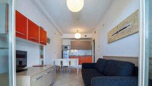 A compact living space with a kitchenette, a dining area, and a seating area. - Stunning flat with terrace overlooking the sea (Bibione)