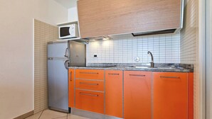 Una cocina con microondas integrado, refrigerador de acero inoxidable y gabinetes color naranja.
