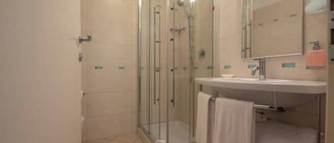 A modern bathroom with a glass-enclosed shower, a sink with a mirror, and a towel rack.