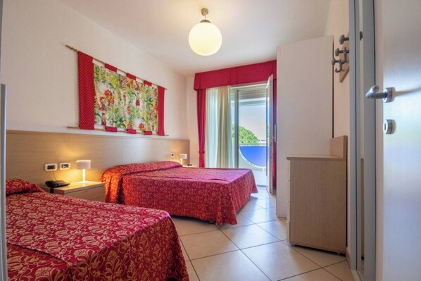 A hotel room with two beds, a large window with a view, a wardrobe, and a wall-mounted artwork.