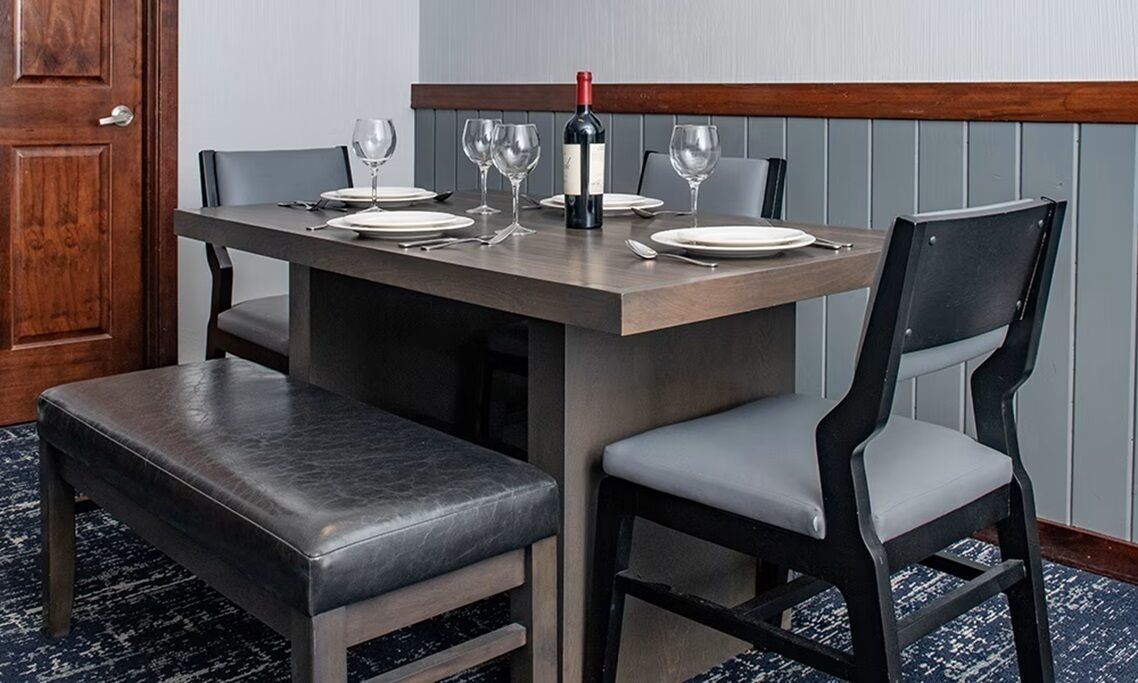 Une table à manger dressée avec des assiettes, des verres et une bouteille de vin.