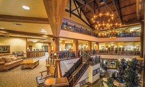 A multi-level hotel lobby with a grand staircase, wooden beams, and a Christmas tree. - Wisconsin Dells Adventure! Glacier Canyon Resort w/Access to Water Parks! (Baraboo)