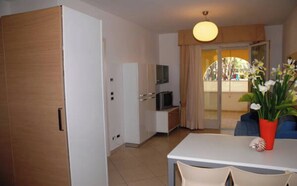 A room with a white table, chairs, a television, and a sliding glass door leading to an outdoor area. - Refined comfort stay with spa (Bibione)