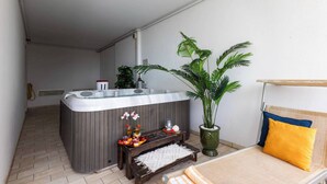 A modern bathroom with a hot tub, a wooden bench, a potted plant, and a towel rack. - Exclusive penthouse with jacuzzi and sea views (Bibione)