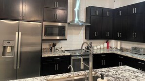 Una cocina moderna con armarios oscuros, electrodomésticos de acero inoxidable y una encimera de mármol.