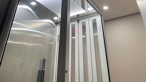 Interior moderno de ascensor con puertas de vidrio y un panel de control.