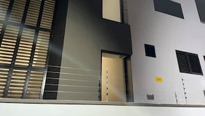 A modern building with a flat facade, large windows with horizontal blinds, and a visible door. - Casa Los Cedros M&G (San Pedro Sula)